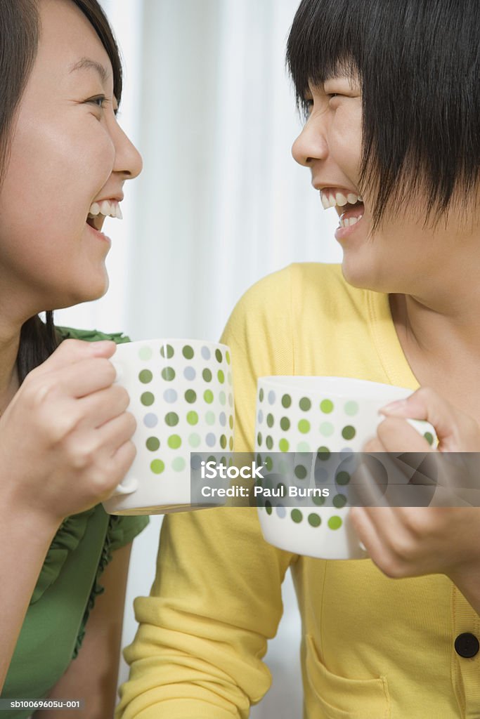 Teenage girl (16-17) and young woman holding coffee mugs, laughing - Foto de stock de 16-17 años libre de derechos