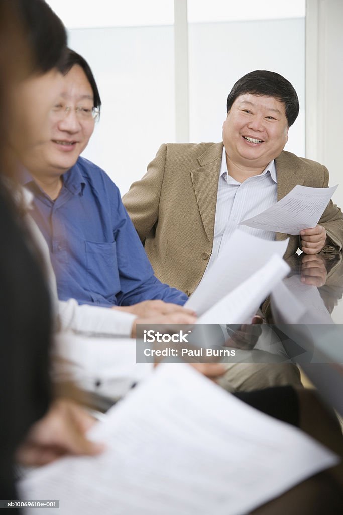 Businesspeople reading documents in conference room, smiling - Lizenzfrei Geschäftsfrau Stock-Foto