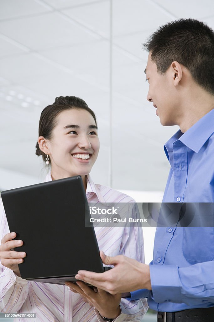 Businessman and businesswoman discussing with laptop, smiling  20-24 Years Stock Photo