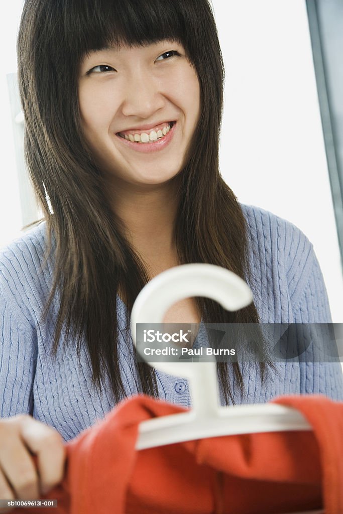 Young woman choosing dress in shop, smiling, close-up - Foto de stock de 20-24 Anos royalty-free