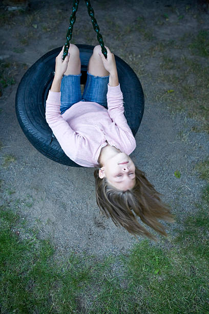 girl (8-9) swinging on tire swing, high angle view - freedom tire swing tire swing imagens e fotografias de stock