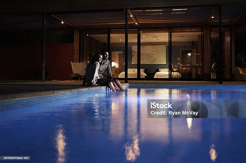 Young couple sitting at edge of pool at night Sedona, Arizona, USA Swimming Pool Stock Photo