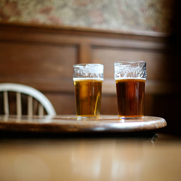 two pints of beer on table - pint glass fotografías e imágenes de stock