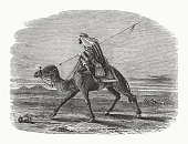 istock Oriental postman riding a camel, wood engraving, published in 1862 1366595166