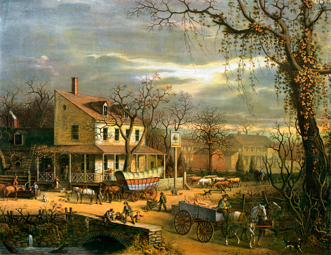 Vintage illustration features a busy autumn American scene outside an inn at a crossroads. In the lower right, a man drives a cart hauling slaughtered pigs; at center is a conestoga wagon in front of the inn.