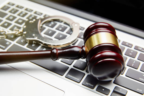 HANDCUFFS AND GAVEL ON COMPUTER KEYBOARD stock photo