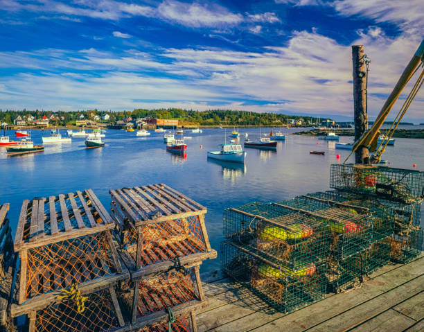 NEW ENGLAND COAST WITH FISHING BOATS AND LOBSTER BASKET AT BASS HARBOR, MAINE LOBSTER BASKET ON DOCK WITH CALM HARBOR WATERS AT BASS HARBOR, MAINE fishing village stock pictures, royalty-free photos & images