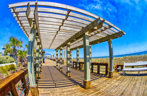 BEACH BOARDWALK PERGOLA HDR A view down a seaside beach boardwalk on a nice sunny day with a wooden shade pergola in a super wide angle. Fisheye lens, Canon 15mm lens. carolina beach north carolina stock pictures, royalty-free photos & images