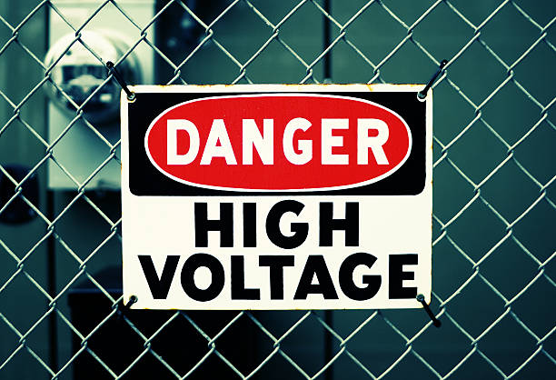 DANGER HIGH VOLTAGE Metal "DANGER HIGH VOLTAGE" sign tied to a fence. Shallow depth of field with electricity meter in the background. Simulated cross-processed effect. high voltage sign photos stock pictures, royalty-free photos & images