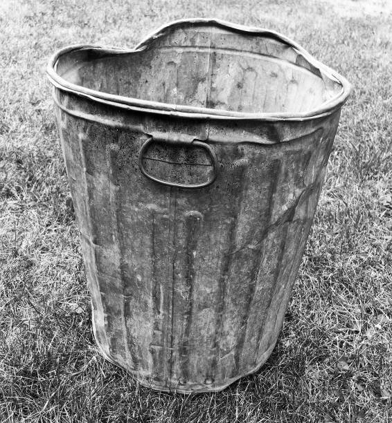 BENT METAL GARBAGE CAN ON A LAWN stock photo