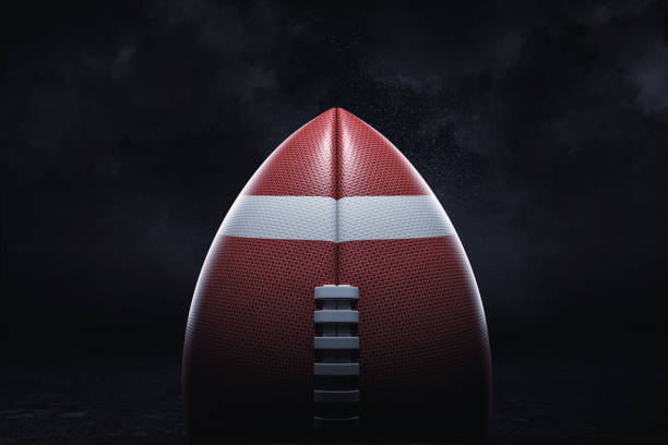 3d rendering of an American football ball with its pointed side up on a dark background. stock photo