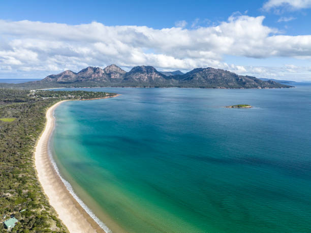 4k high angle aerial drone view of Muirs Beach near Coles Bay with the famous Hazards mountain range in the background, part of Freycinet Peninsula National Park, Tasmania, Australia. stock photo