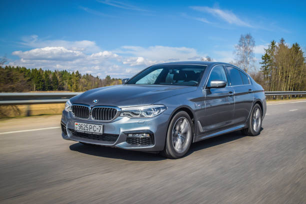 BMW 5-series (G30) Minsk, Belarus - April 4, 2017: 2017 model year seventh generation BMW 5 Series drive along the road on a sunny day. The BMW 5 Series is the embodiment of the modern business saloon. Thanks to its dynamic and elegant appearance, it convincingly meets the expectations that are placed on a vehicle of its class: aesthetic athleticism and driving pleasure with state-of-the-art technology. bmw stock pictures, royalty-free photos & images
