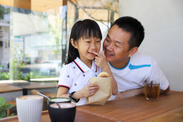 a Asian family eating brunch in a restaurant. a Asian father eating brunch with his daughters in a restaurant. fathers day stock pictures, royalty-free photos & images