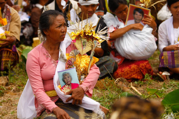 a Balinese woman is holding the offerings and pictures of she's family who will be cremated in the cremation ceremony which is called Ngaben. stock photo