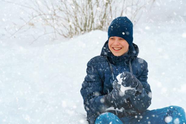 a boy plays snowballs outside, beautiful winter weather and white snow around stock photo