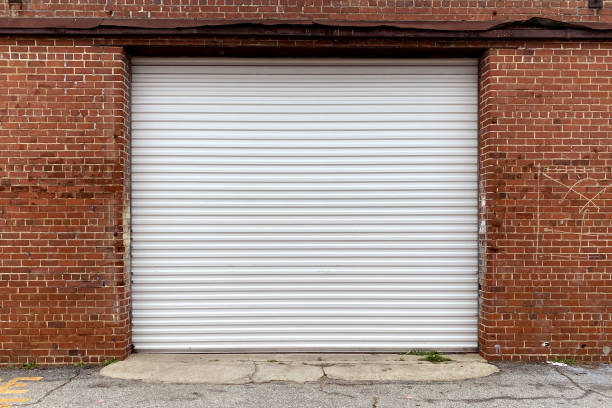 a brick wall warehouse with receiving door in an alley with metal garage doors stock photo