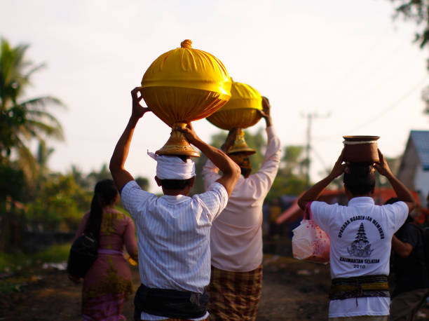 a group of Balinese men are lining up and carrying the offerings with their head to cremation ceremony location stock photo