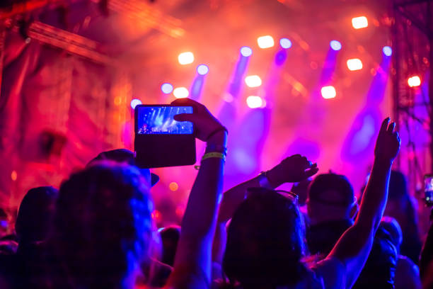 a group of fans raised their hands up at a music concert stock photo