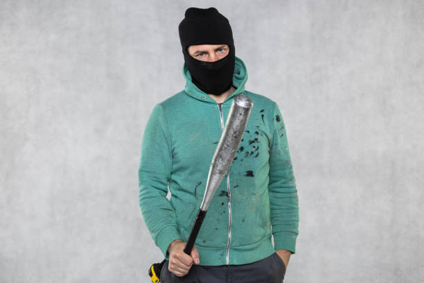 a masked hooligan holds a baseball bat in his hand a masked hooligan holds a baseball bat in his hand ski mask criminal stock pictures, royalty-free photos & images
