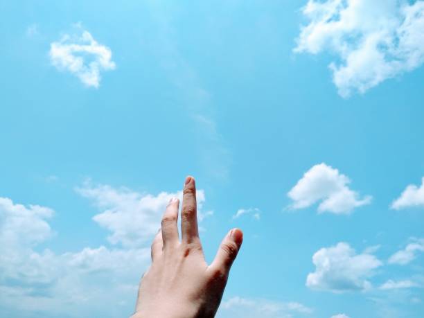a photo of a hand that points to the sky is like reaching a dream as high as the sky stock photo