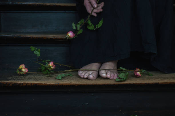 a woman holding a bouquet of dead roses stock photo