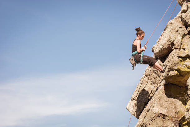 a woman practicing climbing on a mountain of rocks, water dam stock photo