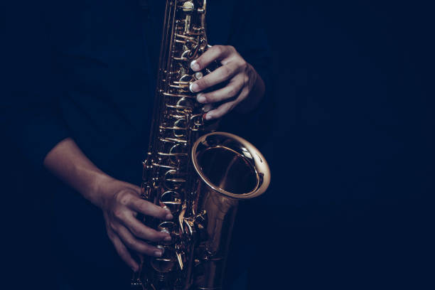 a young musician man hands hold and playing saxophone on black background stock photo