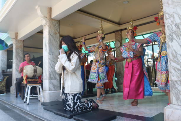 a young thai woman praying at buddha eriwan shrine with corona mask - personne à genou en train de prier photos et images de collection