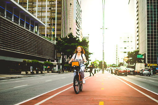 a woman on a bicycle, smiling by in são paulo