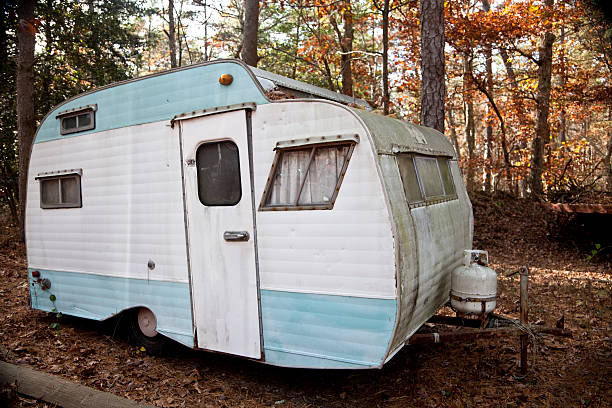 Abandoned Retro Travel Trailer, Mobile Home Old camper trailer rotting in the woods in a junkyard. Autumn color. terryfic3d stock pictures, royalty-free photos & images