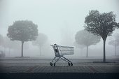 istock Abandoned shopping cart on parking lot in thick fog 1287629056