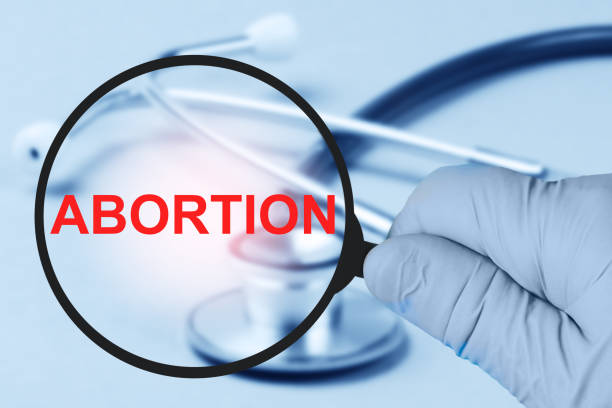 problema del aborto, concepto médico. lupa en la mano del médico. - abortion clinic fotografías e imágenes de stock