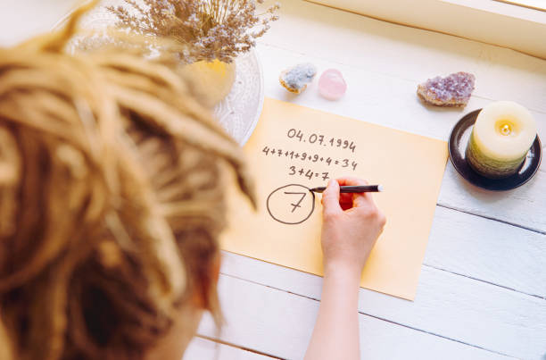 Above view of girl calculate Life path number on paper in home. Spiritual numerology concept. stock photo
