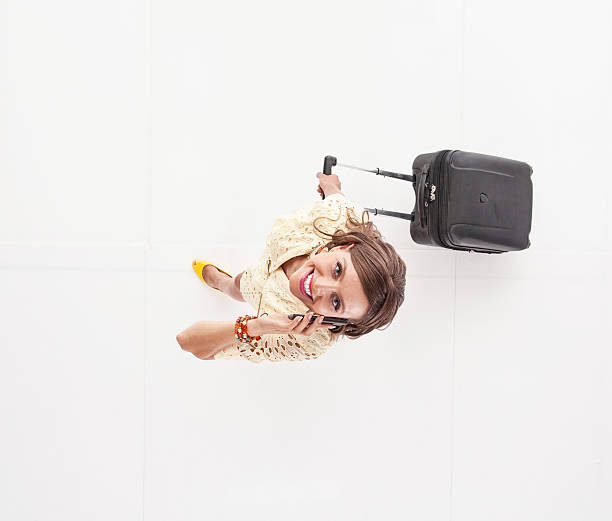 Above View Of Woman On Mobile Holding Trolley Bag Stock Photo