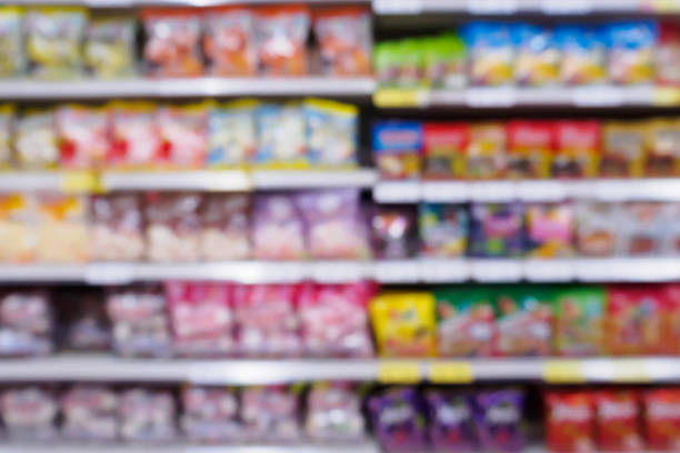 Abstract blur supermarket with variety of snacks chips food product on the shelves in store Abstract blur supermarket with variety of fast food snacks chips product on the shelves in store defocused background candy store stock pictures, royalty-free photos & images