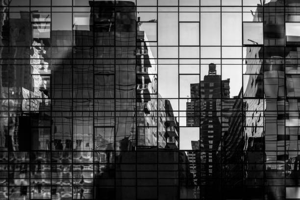 Abstract cityscape reflections in windows on a modern steel and glass skyscraper - in black and white Abstract reflections of buildings in glass windows near the High Line park in New York City cityscape photos stock pictures, royalty-free photos & images