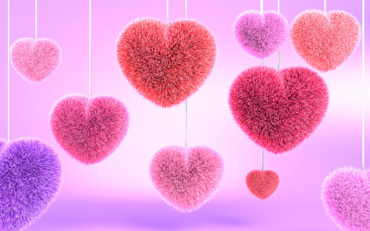 Abstract Valentine's Day greeting card background with colorful soft candy pillow heart ornaments hanging and turning on pink background. Love, Valentine’s Day and relationships concept. Easy to crop for all your social media or print sizes.