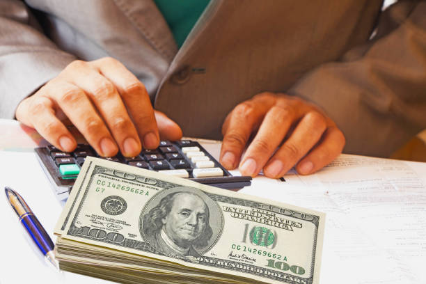 Accountant calculating with dollar currency kept near him Accountant calculating with dollar currency kept near him dollar  stock pictures, royalty-free photos & images