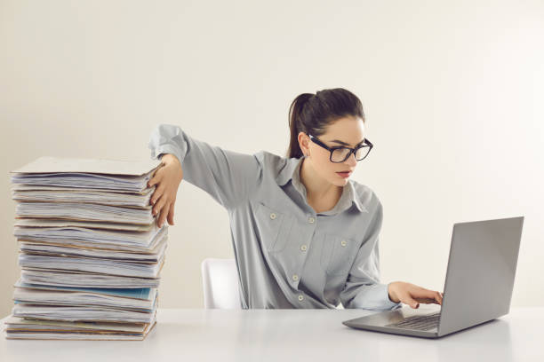 Accountant no more needs piles of papers and is working with electronic documents on laptop stock photo