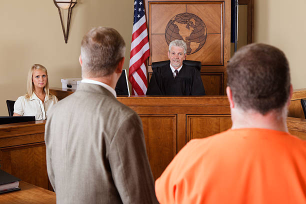 Accused Criminal and Lawyer in a Courtroom A lawyer standing with his client before the judge in a criminal trial. sentencing stock pictures, royalty-free photos & images
