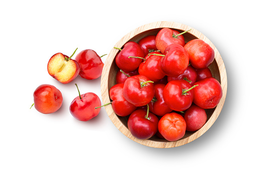 Acerola cherry in wooden bowl isolated on white bckground. Top view. Flat lay.