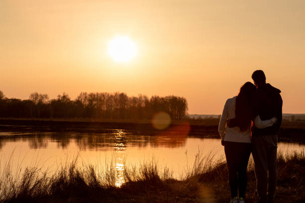 Acouple of lovers stands on the background of a sunny sunset near the river. stock photo