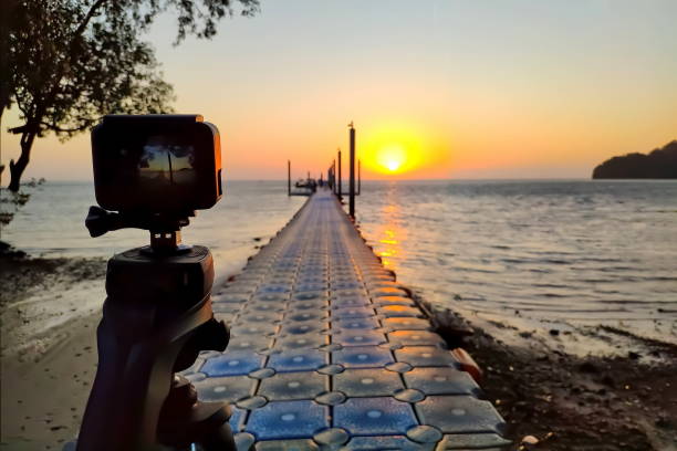 Action camera mounted on a tripod photograph the pier and sunrise on the beach stock photo