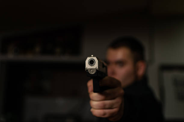 portret akcji poważnego młodego detektywa, agenta specjalnego trzymającego broń celującą z broni, zaangażowanego w strzelanie, wchodzącego do mieszkania z ostrożnością, szukającego przestępców. - gun violence zdjęcia i obrazy z banku zdjęć
