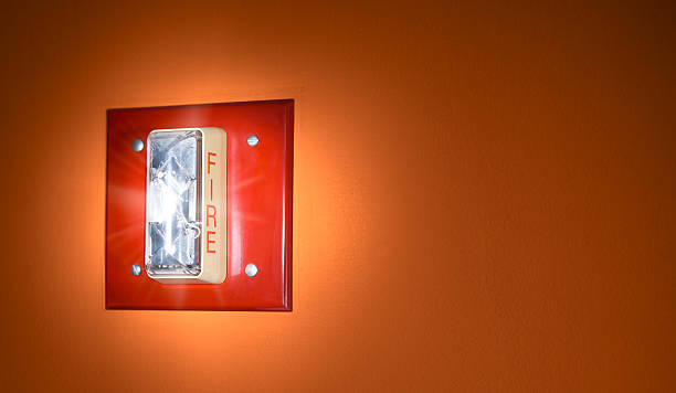 Activated Red Glowing Fire Alarm Signal on Wall stock photo