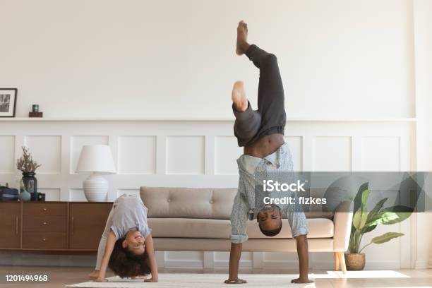 Active biracial dad and daughter exercise at home
