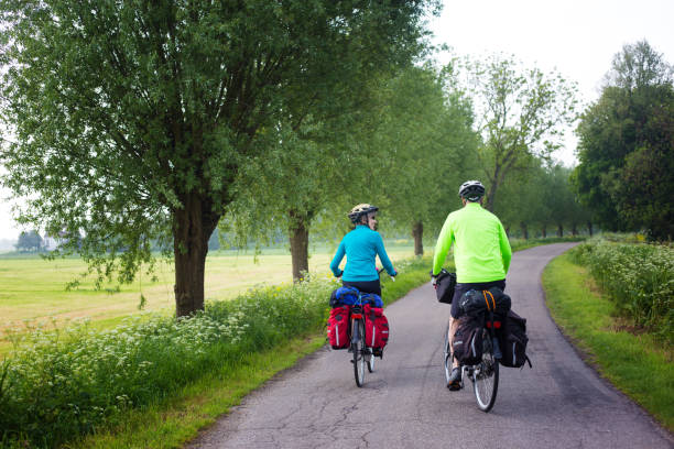 actieve senior fietsers met helmen, fietstassen, gear on country lane - pensioen nederland stockfoto's en -beelden