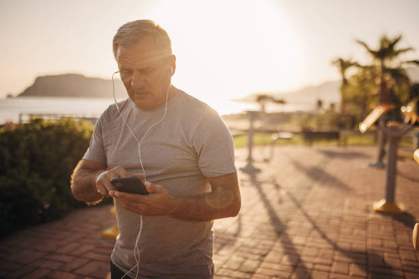 active senior man using phone - senior listening music beach bildbanksfoton och bilder