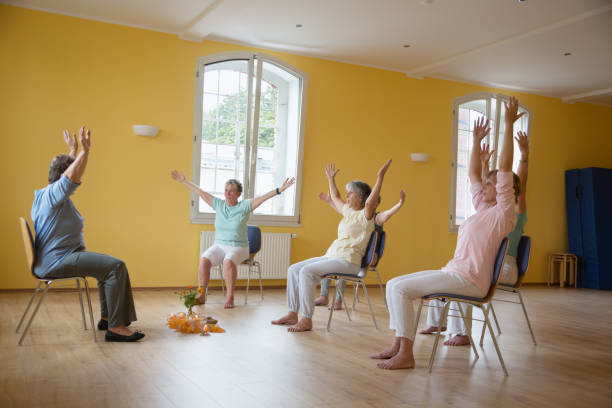 Active senior women: yoga class on chairs stock photo